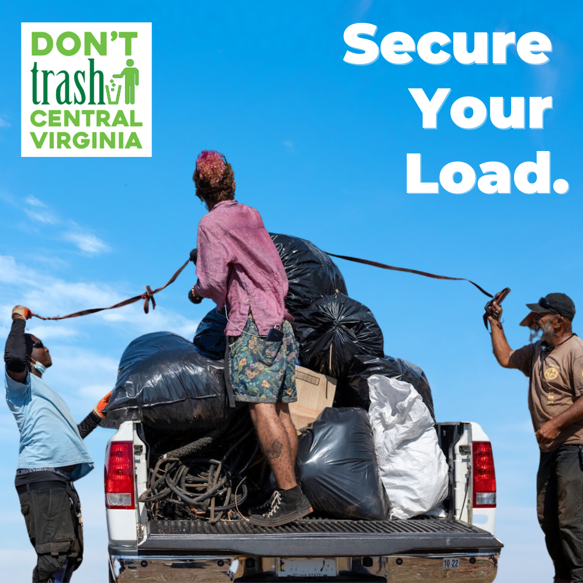 Person standing on truck bed full of debris, working with two other workers tying a cover down over to prevent litter.